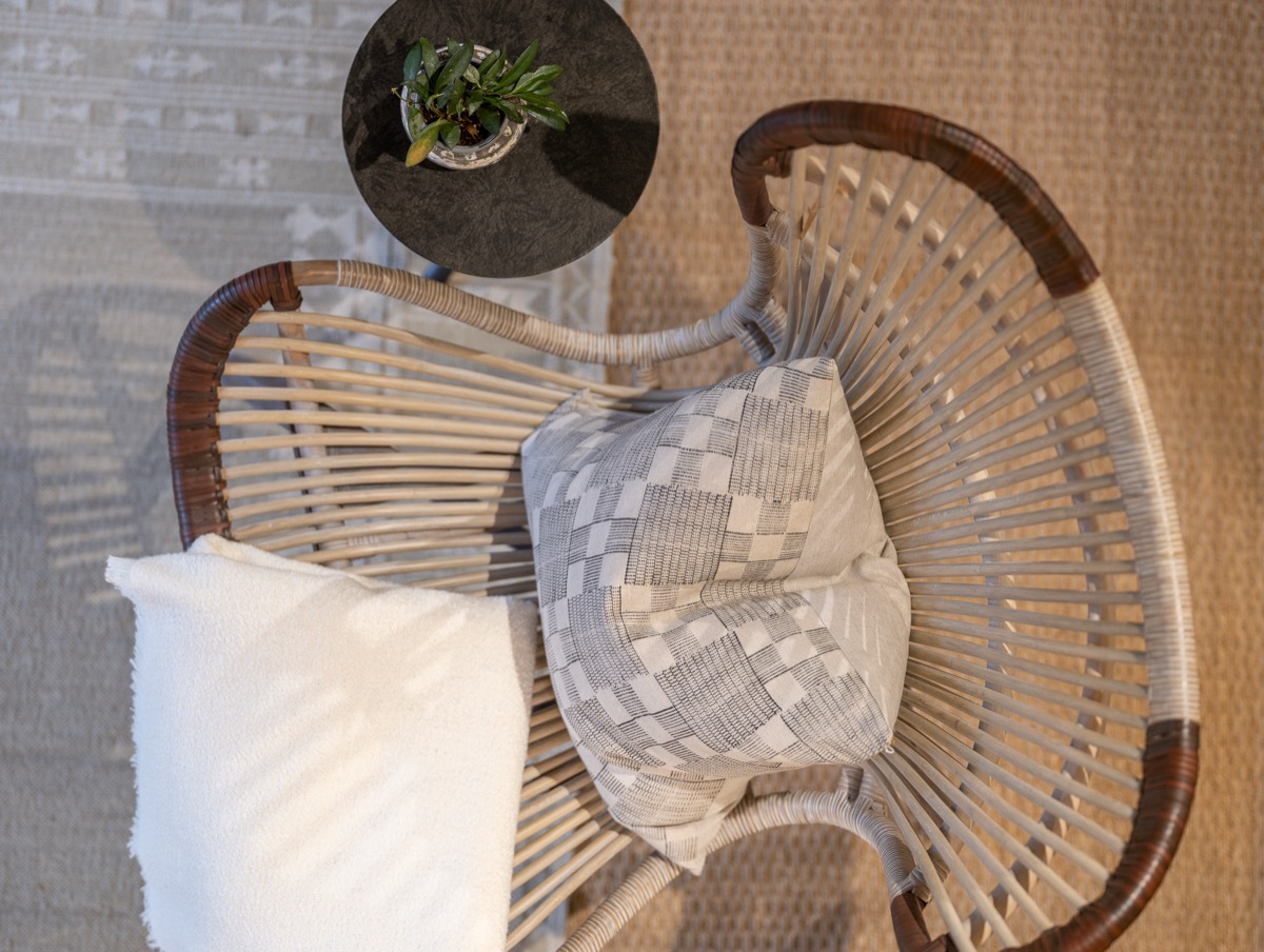 Woven rattan chair with plaid and houndstooth pillows