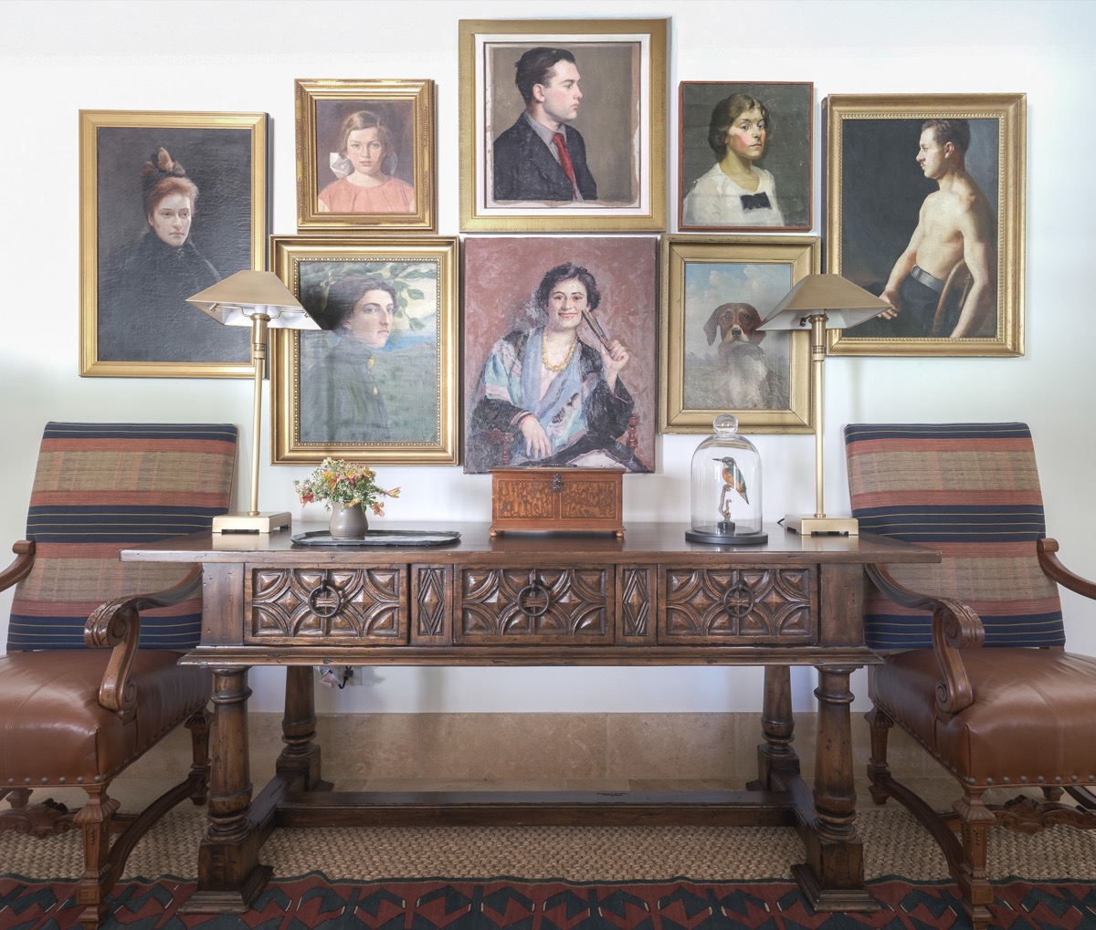 Gallery wall of vintage portraits above a carved antique console table