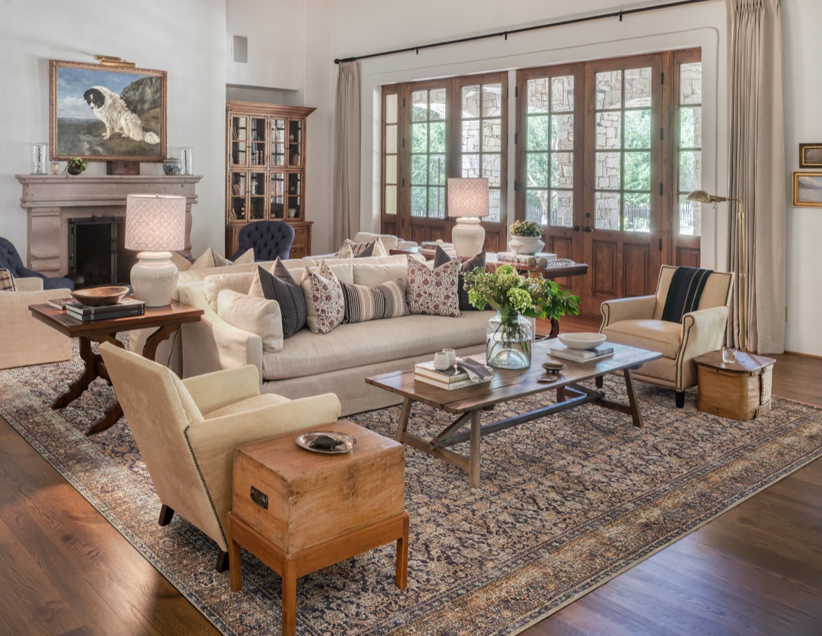 Living room designed by Hart Habitats with a mix of antique and upholstered seating around a patterned rug