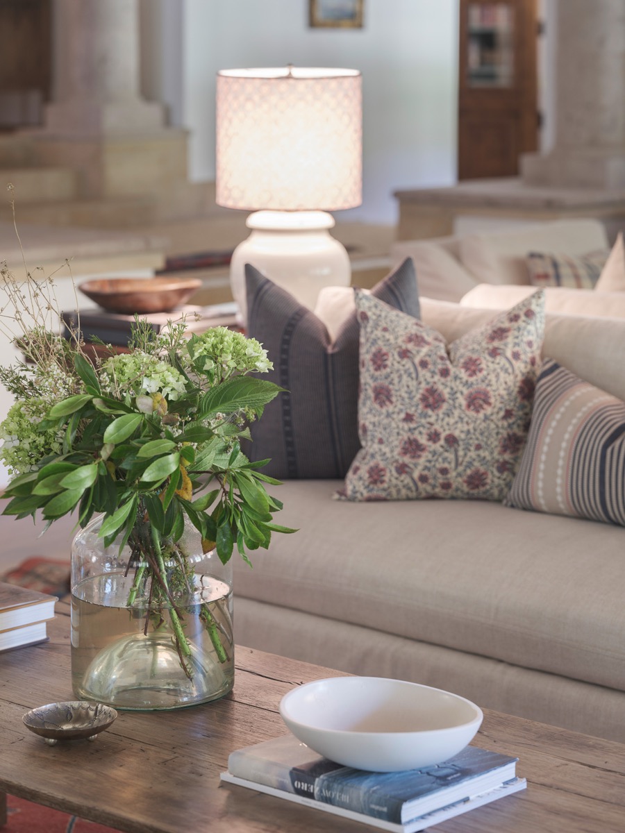 Coffee table styled with fresh greenery and a floral throw pillow in a Hart Habitats living room design