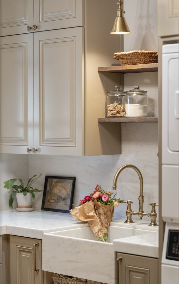 Kitchen detail with a farmhouse sink, brass faucet and open shelving