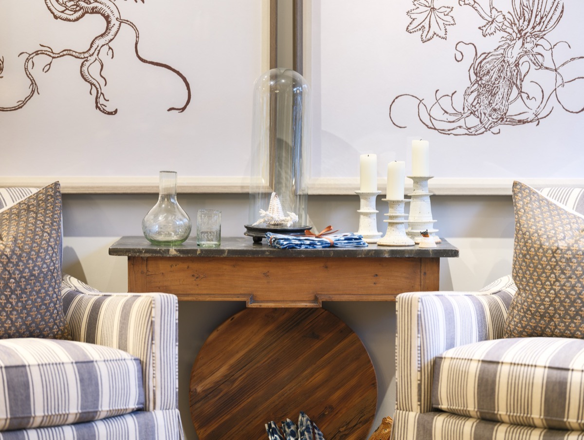 Console table between striped armchairs with a mirror and candles