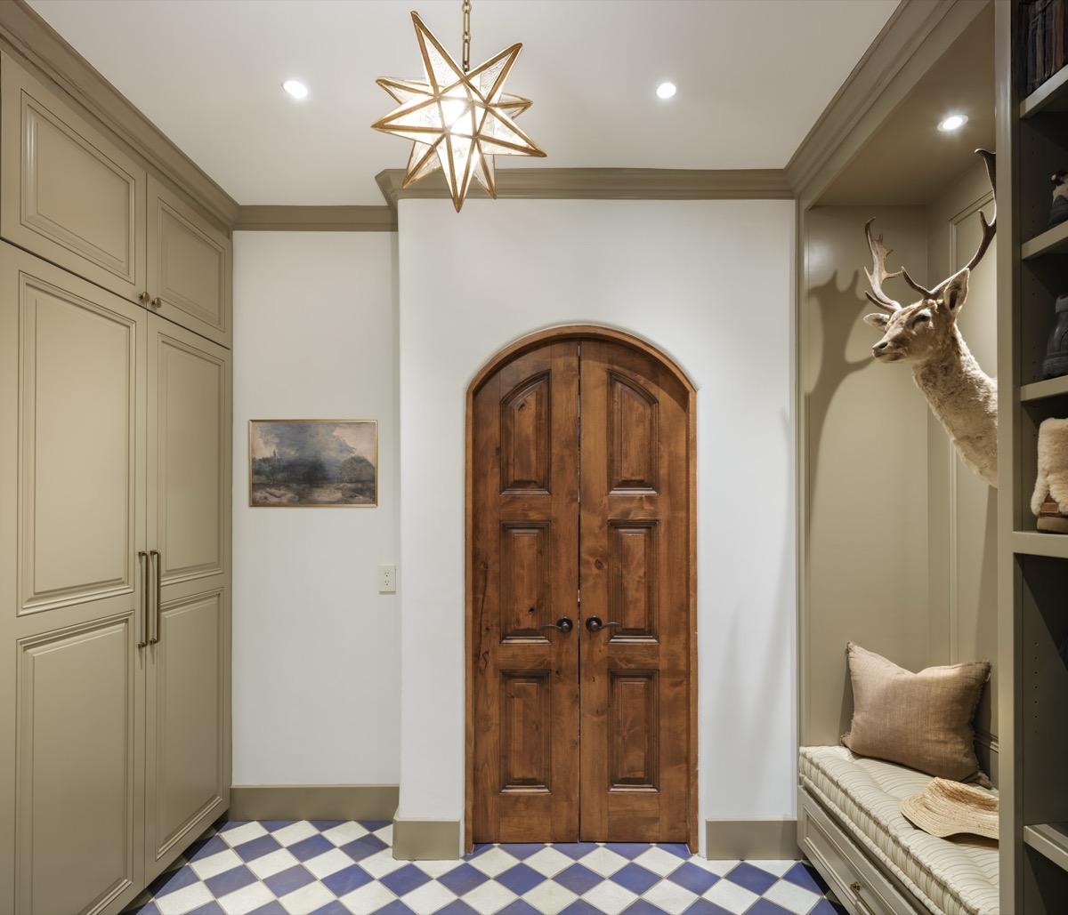 Entryway with a star pendant light, arched wood door and checkerboard tile floor