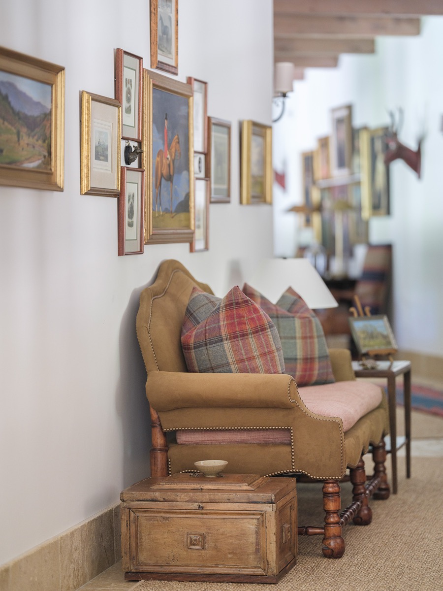 Hallway styled with a gallery wall, antique trunk and upholstered armchair