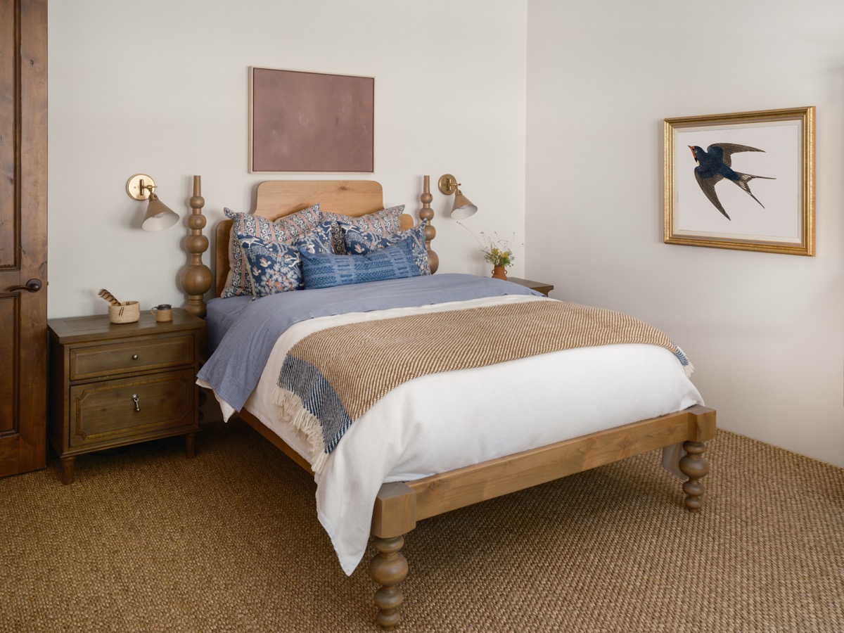 Bedroom with a wood poster bed, blue bedding and bird artwork