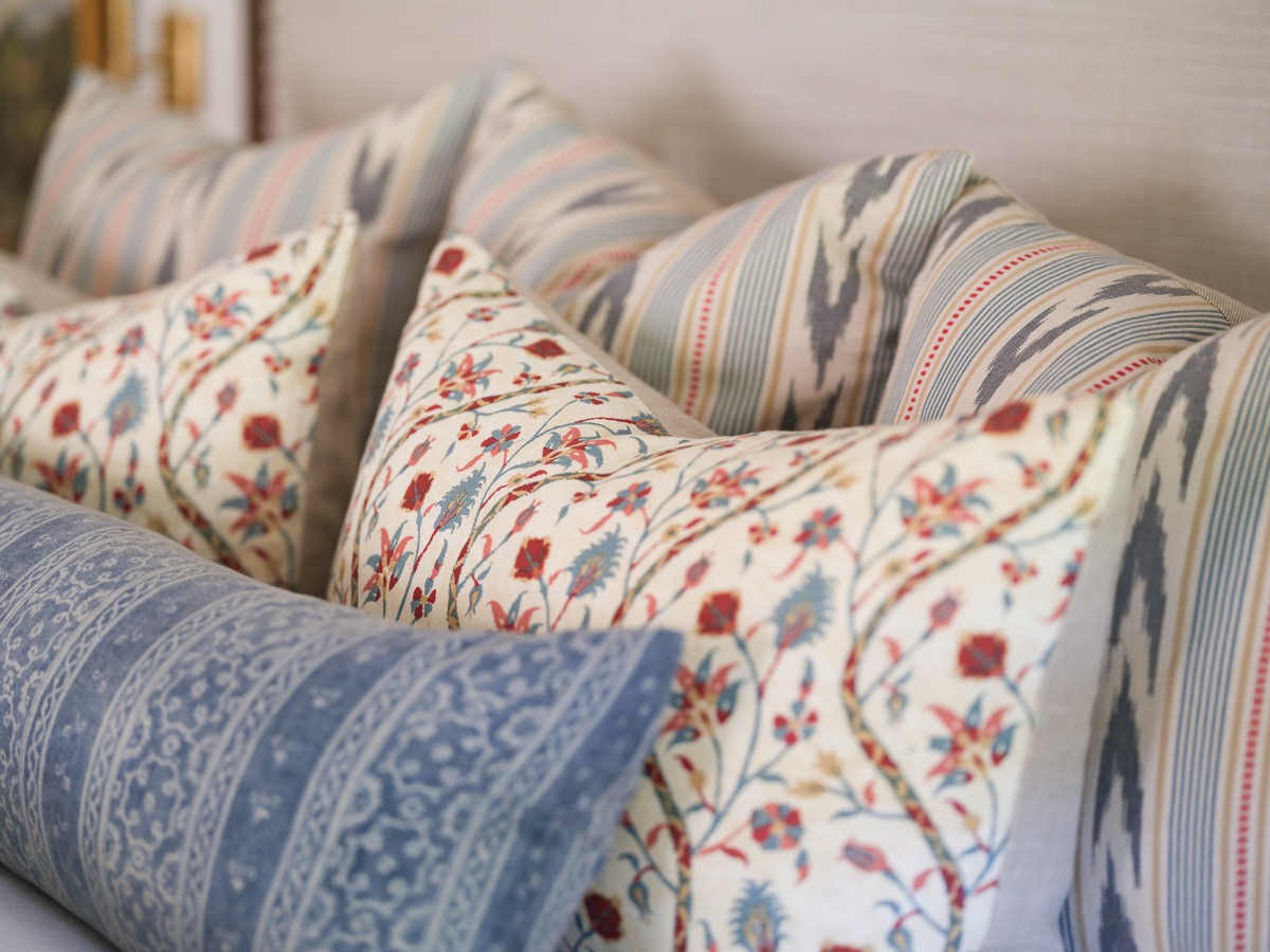 Detail of mixed floral and striped throw pillows in a Hart Habitats bedroom design